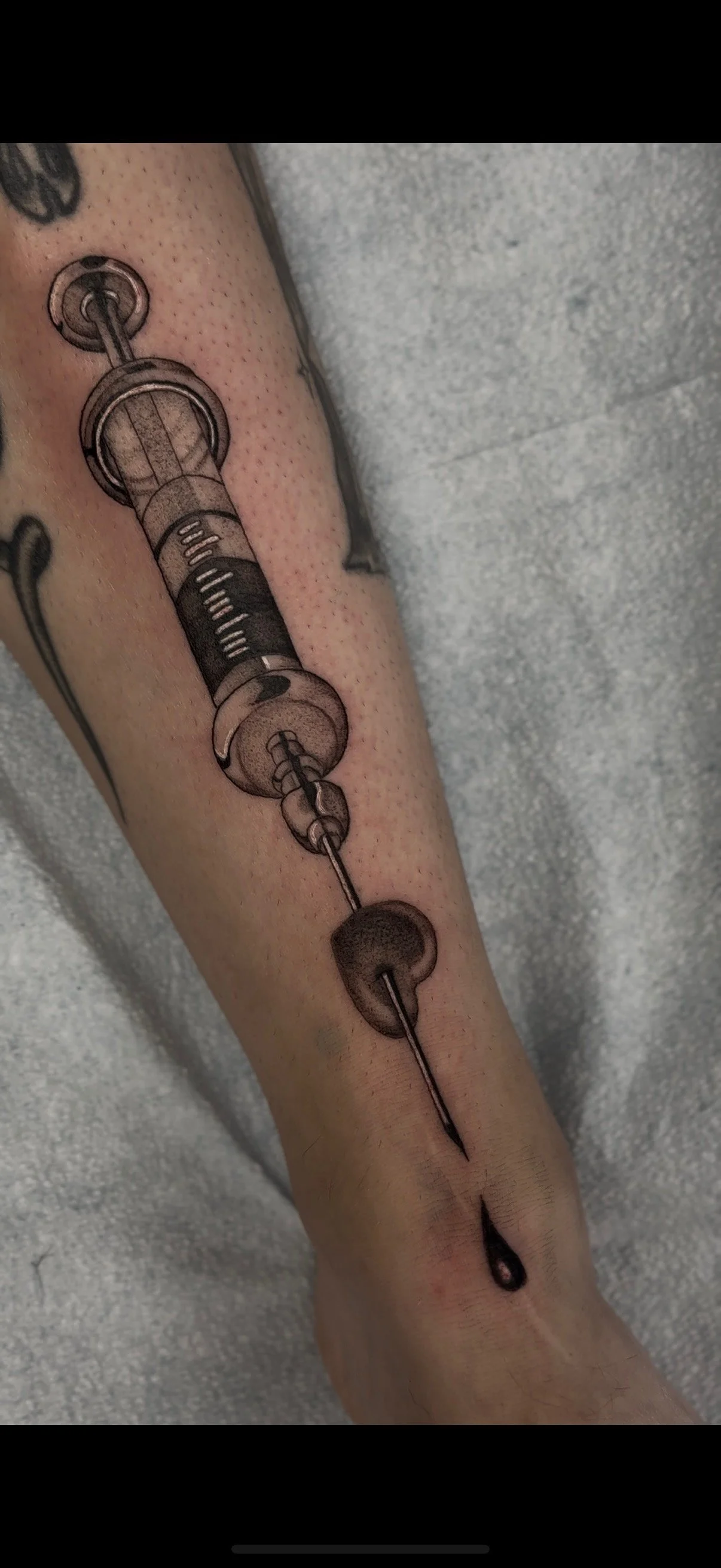 Tattoo of a blue koi fish with a smaller fish in the background, surrounded by stylized waves and clouds, on a person's lower leg.