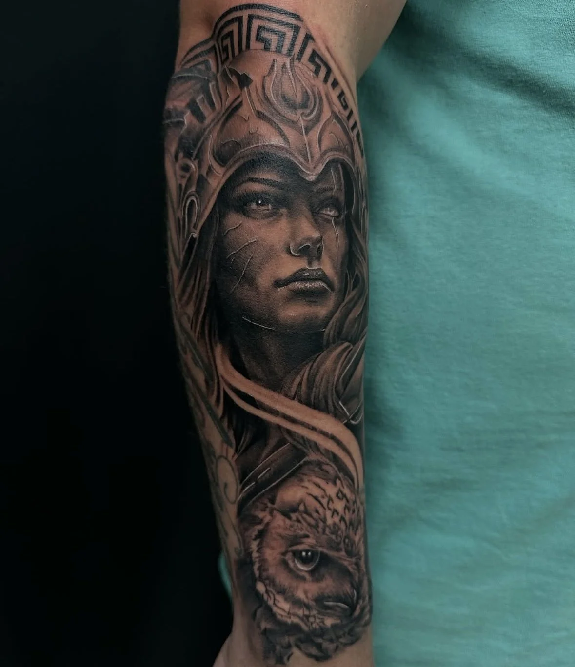 Tattoo of a woman with a helmet and a wolf on an arm.