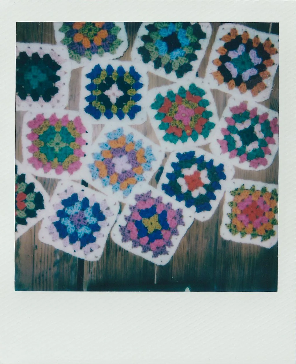 A polaroid photo of brightly colored crocheted granny squares.