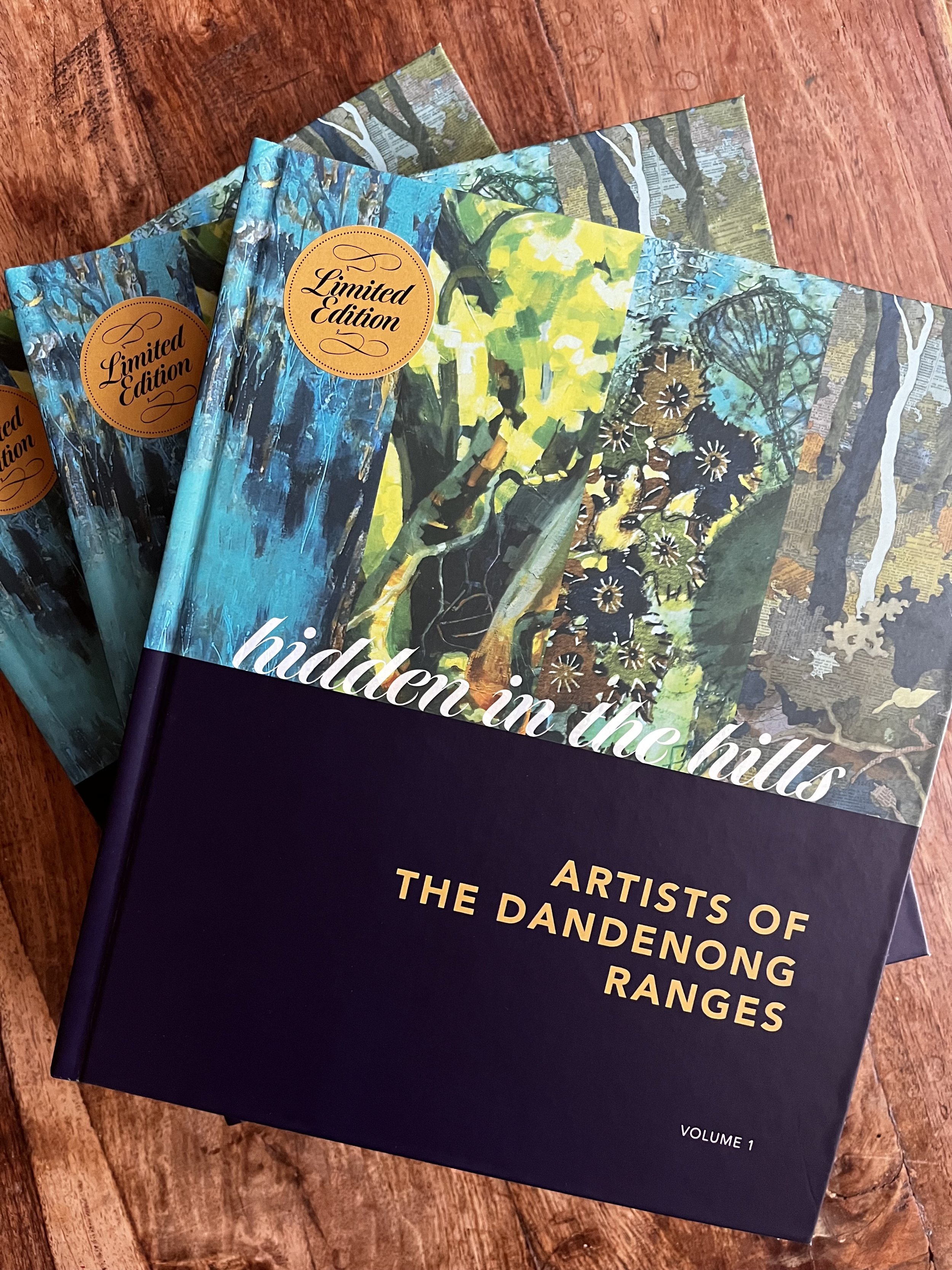 Multiple books titled "Hidden in the Hills" with artwork of forests and nature scenes, labeled as "Limited Edition," on a wooden surface.