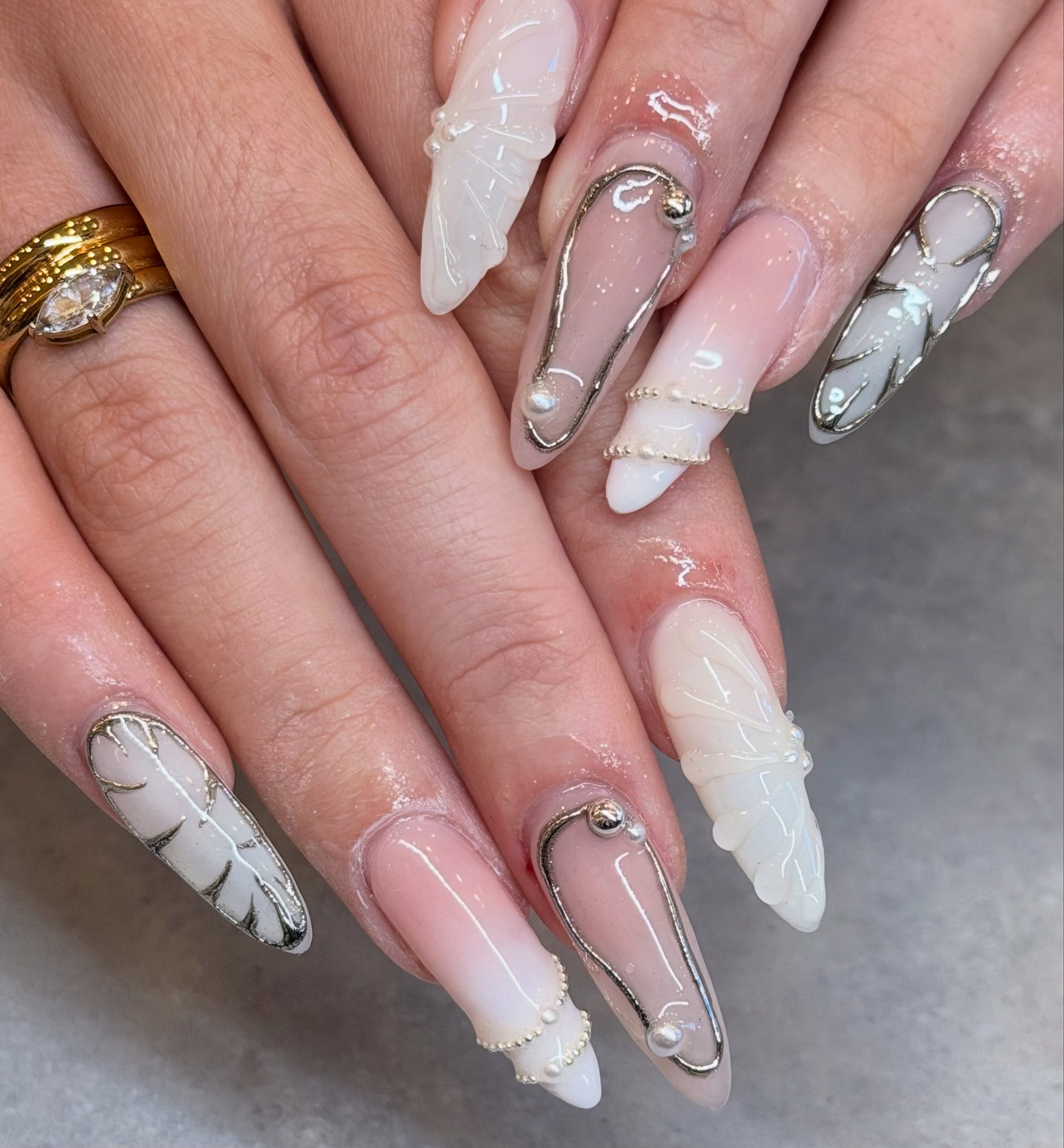 What theme would you say these nails are? Whatever it is, we&rsquo;re loving the combination of white, pearl and silver. 🤍🩶

Nails by Senior Artist, Sarah. 🪽

#longnails #chromenails #3dnailart #banglenails #cybernails cyber nails, chrome nails, 3