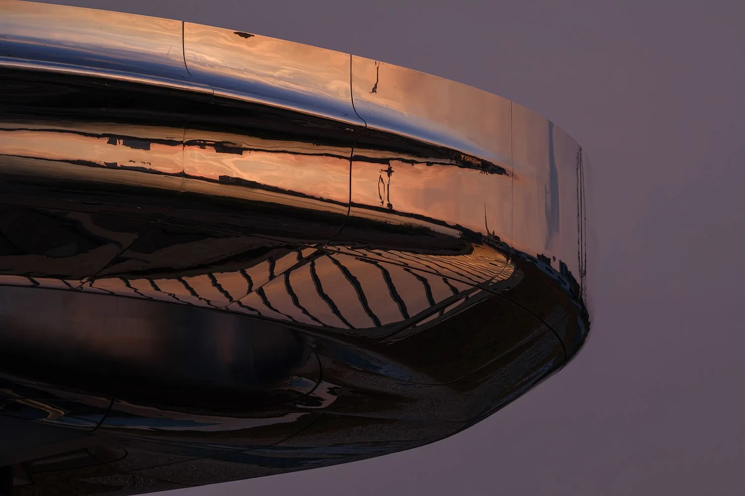 Tight architectural detail of the mirrored Fenix museum reflecting warm evening light in Rotterdam.