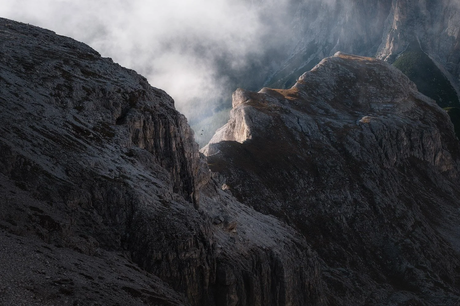 A gap in the clouds revealing a sunlit ridge between dark mountain slopes near Lagazuoi.