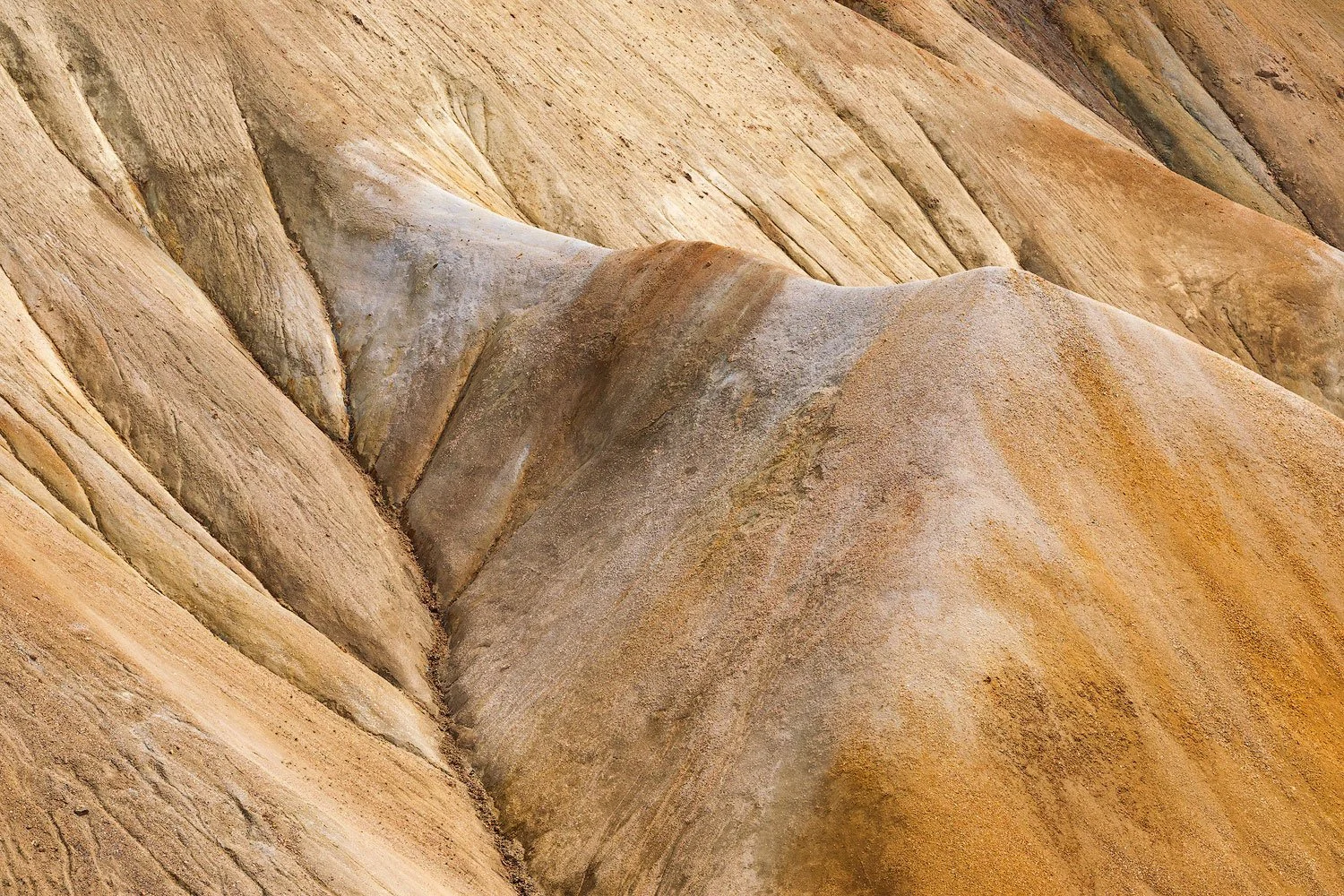 Tight telephoto composition of smooth ochre and cream rhyolite slopes at Landmannalaugar in the Icelandic Highlands.