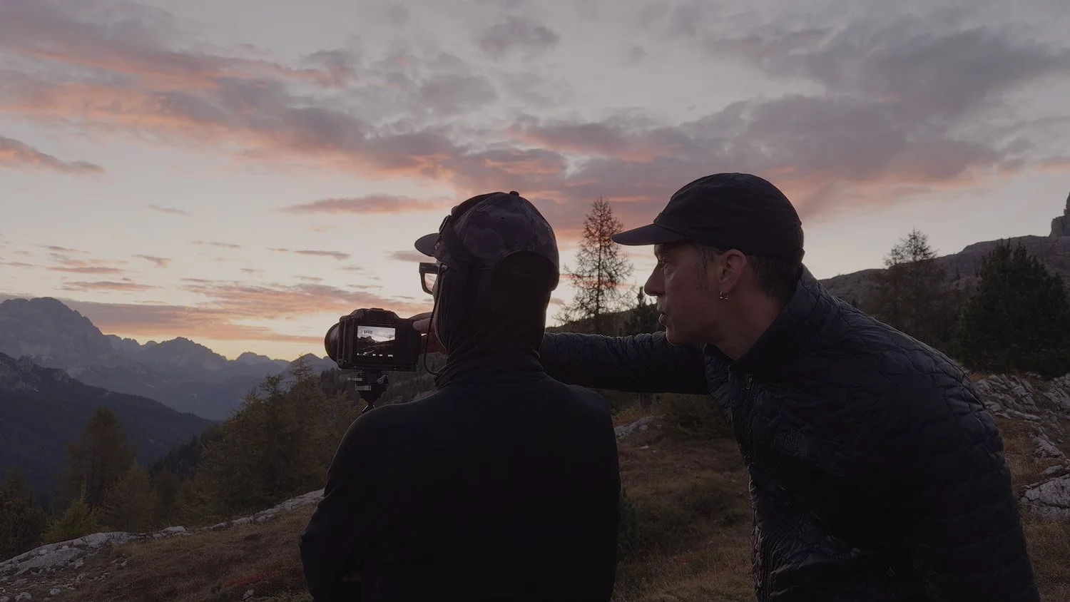 Andrea Livieri with a workshop participant photographing dawn near Passo Falzarego beneath pink and gray clouds.