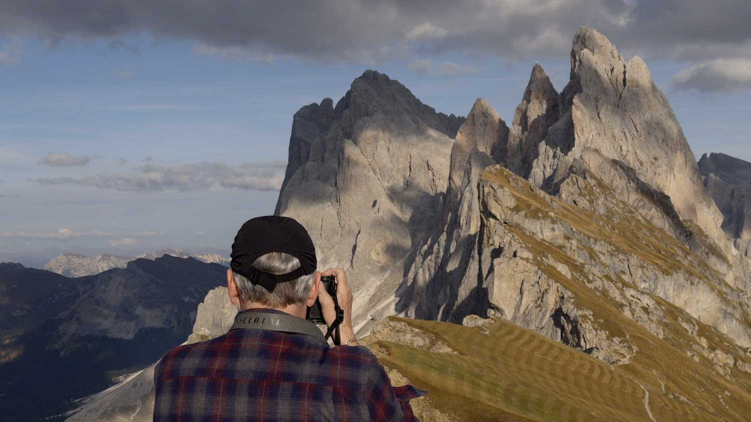 A workshop participant photographing Seceda’s jagged ridge above the grassy slopes of the Italian Dolomites.