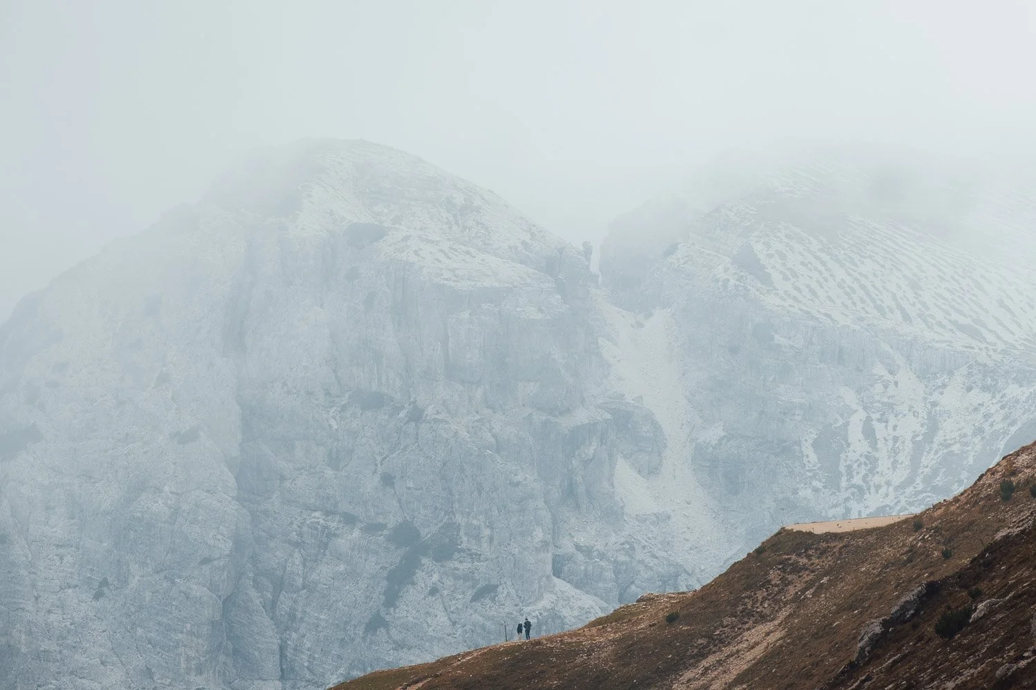 Low clouds partially obscuring the pale limestone mountains along the route to Tre Cime di Lavaredo.