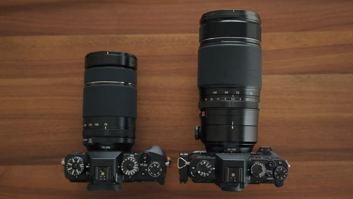 Fujinon 70–300mm and 50–140mm lenses mounted on Fujifilm X cameras for a size comparison.