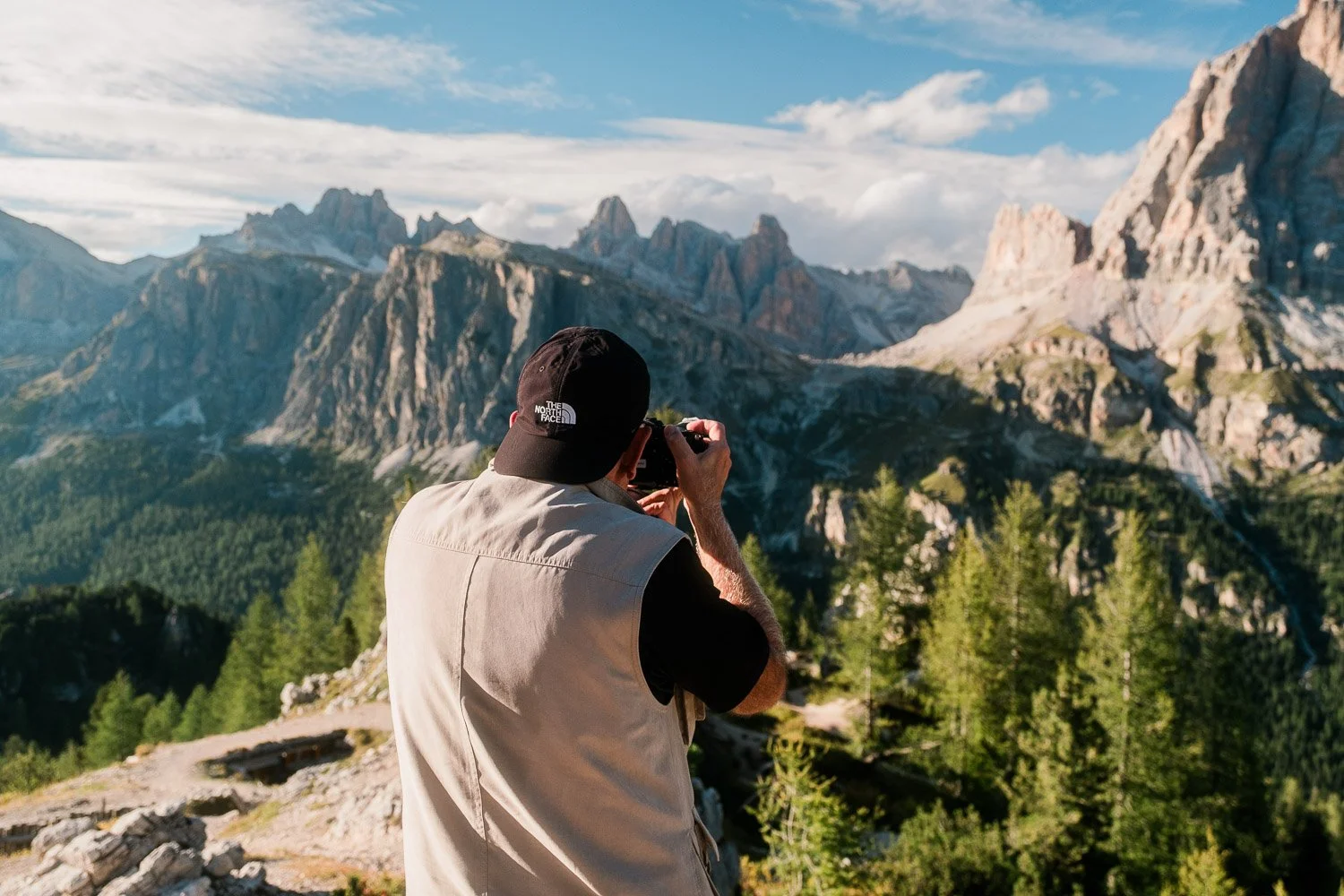 A workshop participant photographing mountain cliffs and larch trees at Cinque Torri.