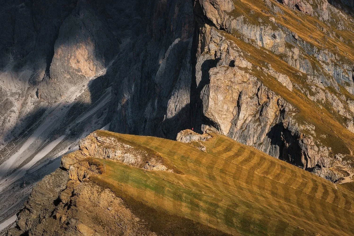 Sunlight revealing folded grassy ridges and steep limestone cliffs at Seceda.