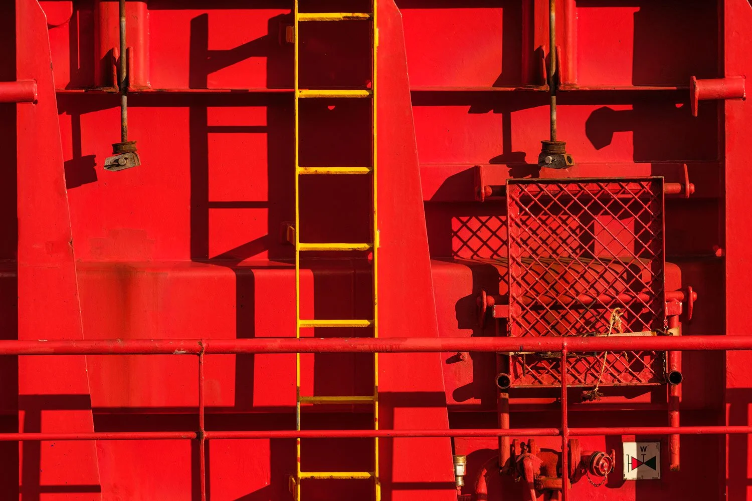 Graphic close-up of a red ship exterior with a yellow ladder, pipes and industrial equipment in Rotterdam.