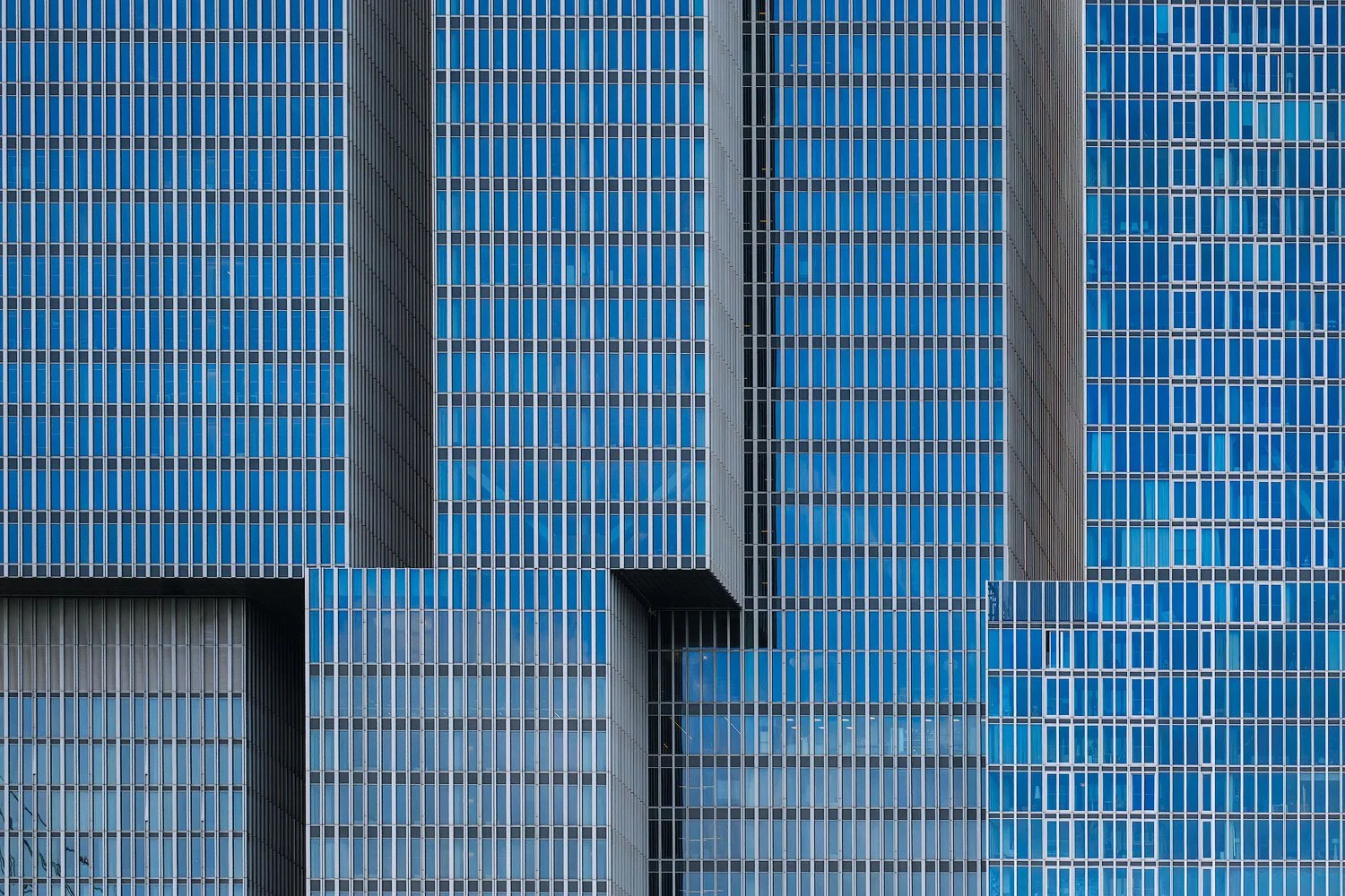 Abstract architectural close-up of a blue glass façade with repeating lines and window patterns in Rotterdam.