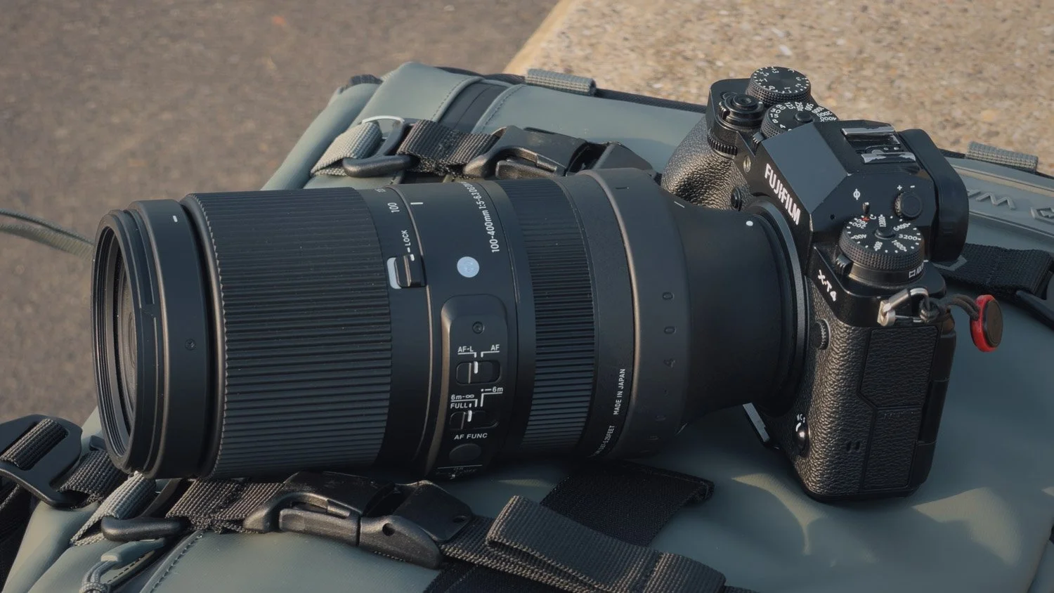 Sigma 100–400mm for Fujifilm X mounted on an X-T4 and resting on a camera backpack.