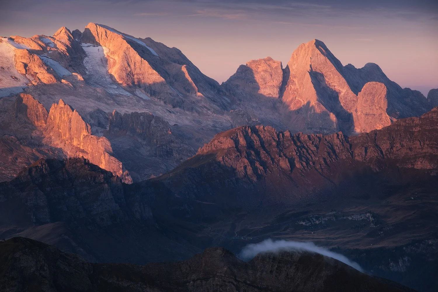 Sunrise lighting Marmolada above shadowed valleys, photographed from Lagazuoi.