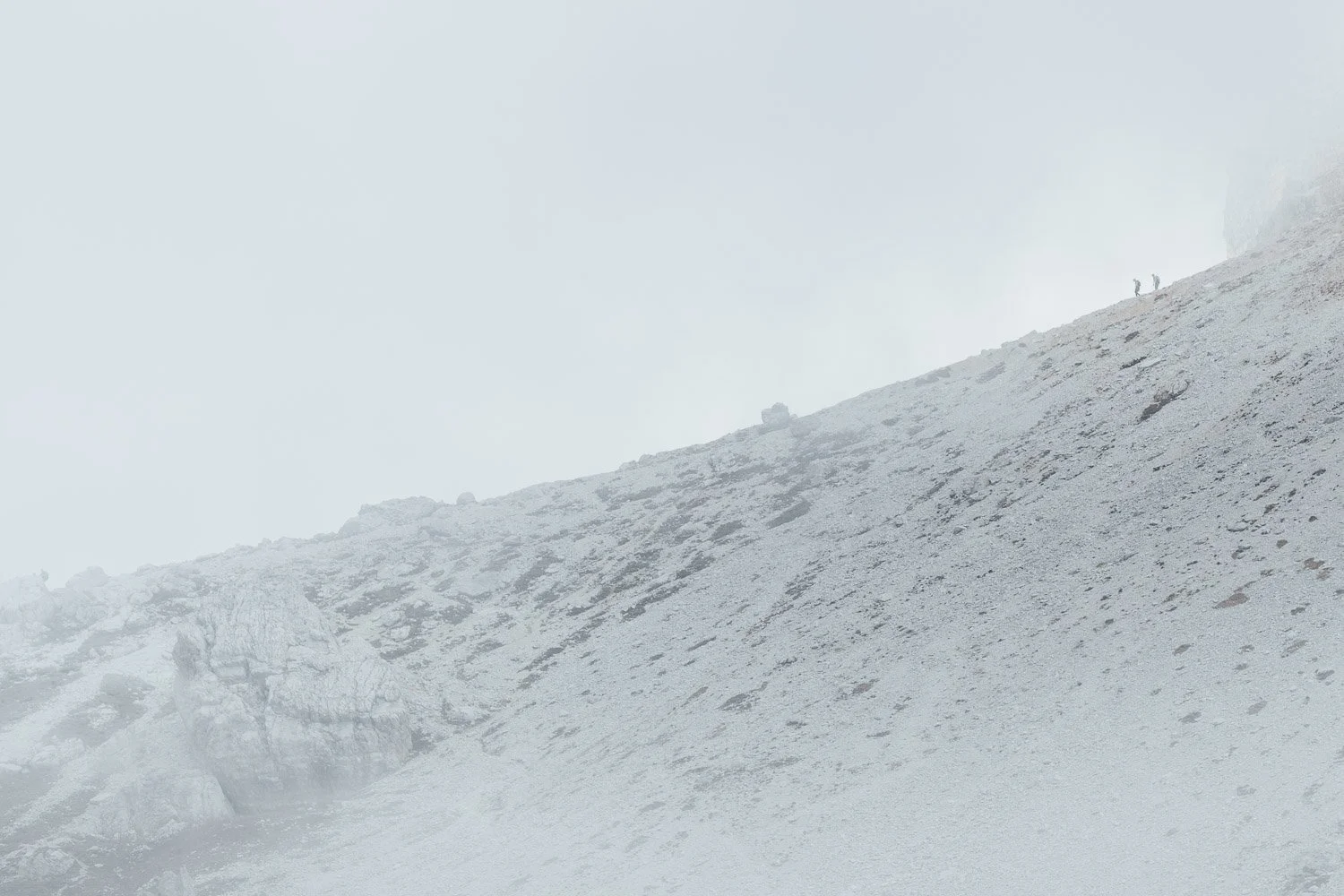 A pale scree slope disappearing into low cloud during the group’s walk at Tre Cime di Lavaredo.