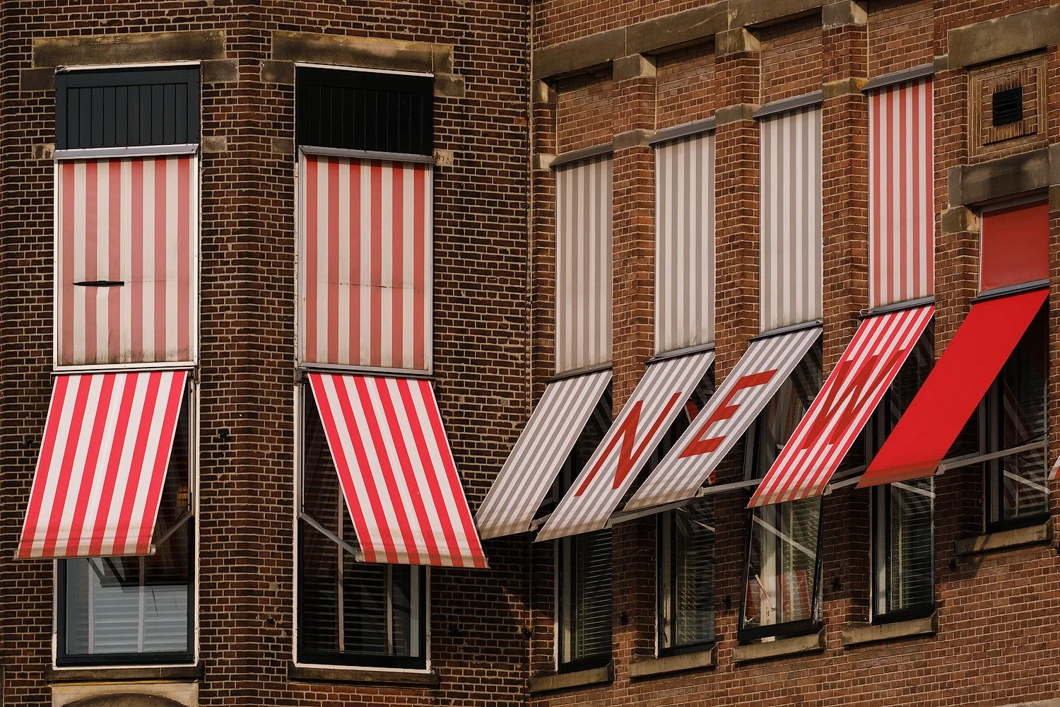 Red-and-white striped awnings across a brick residential façade in Rotterdam.