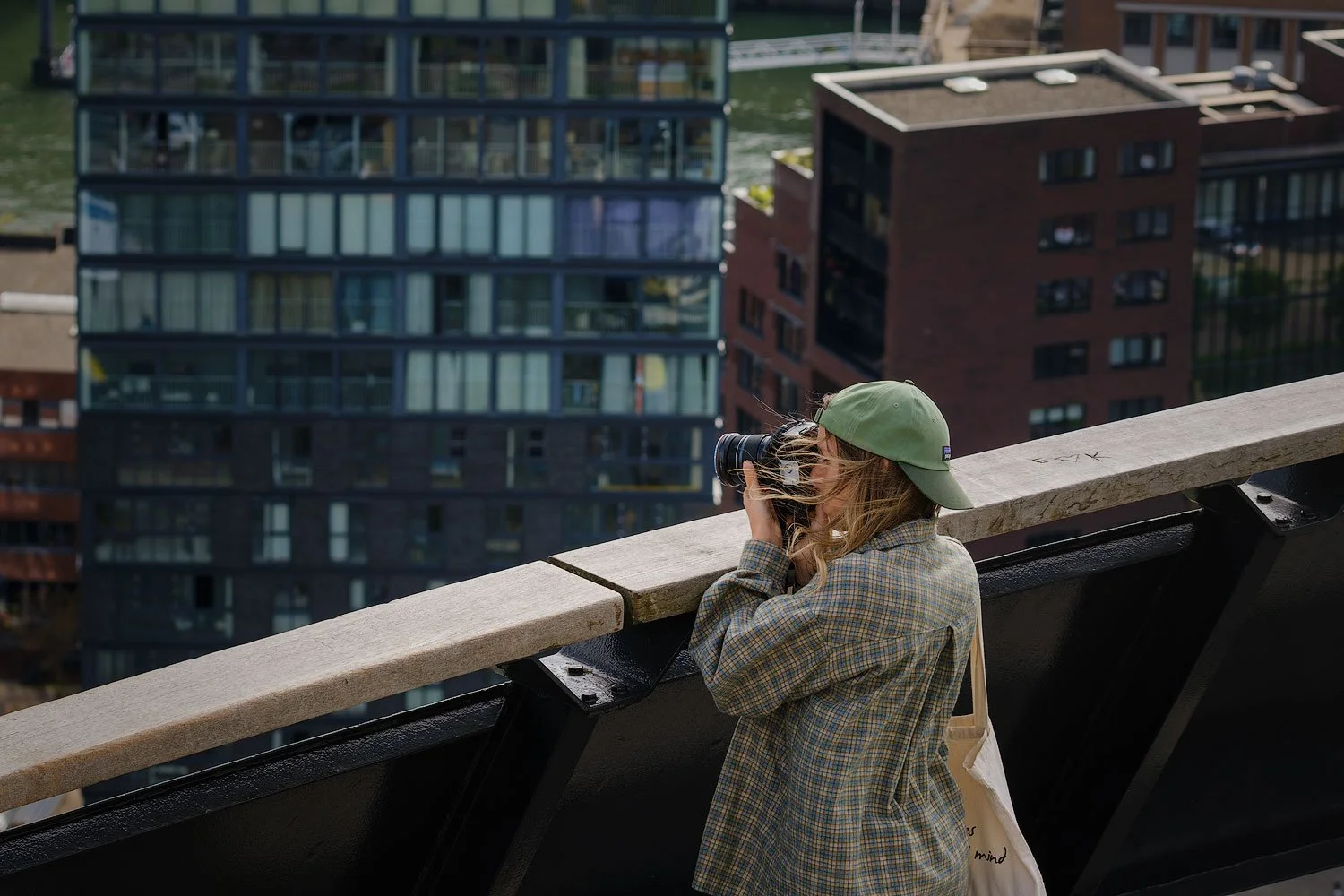 Photographer in a green cap photographing the Rotterdam skyline from the Euromast observation deck.