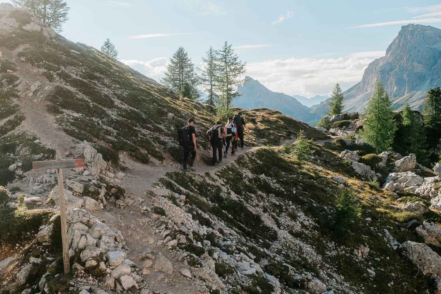 The workshop group walking along a rocky trail among larch trees and cliffs at Cinque Torri.
