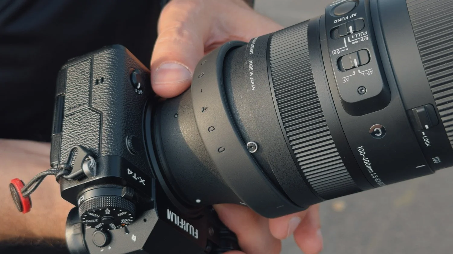 Close-up of the Sigma 100–400mm mounted on an X-T4, showing its focus controls and tripod collar mount.