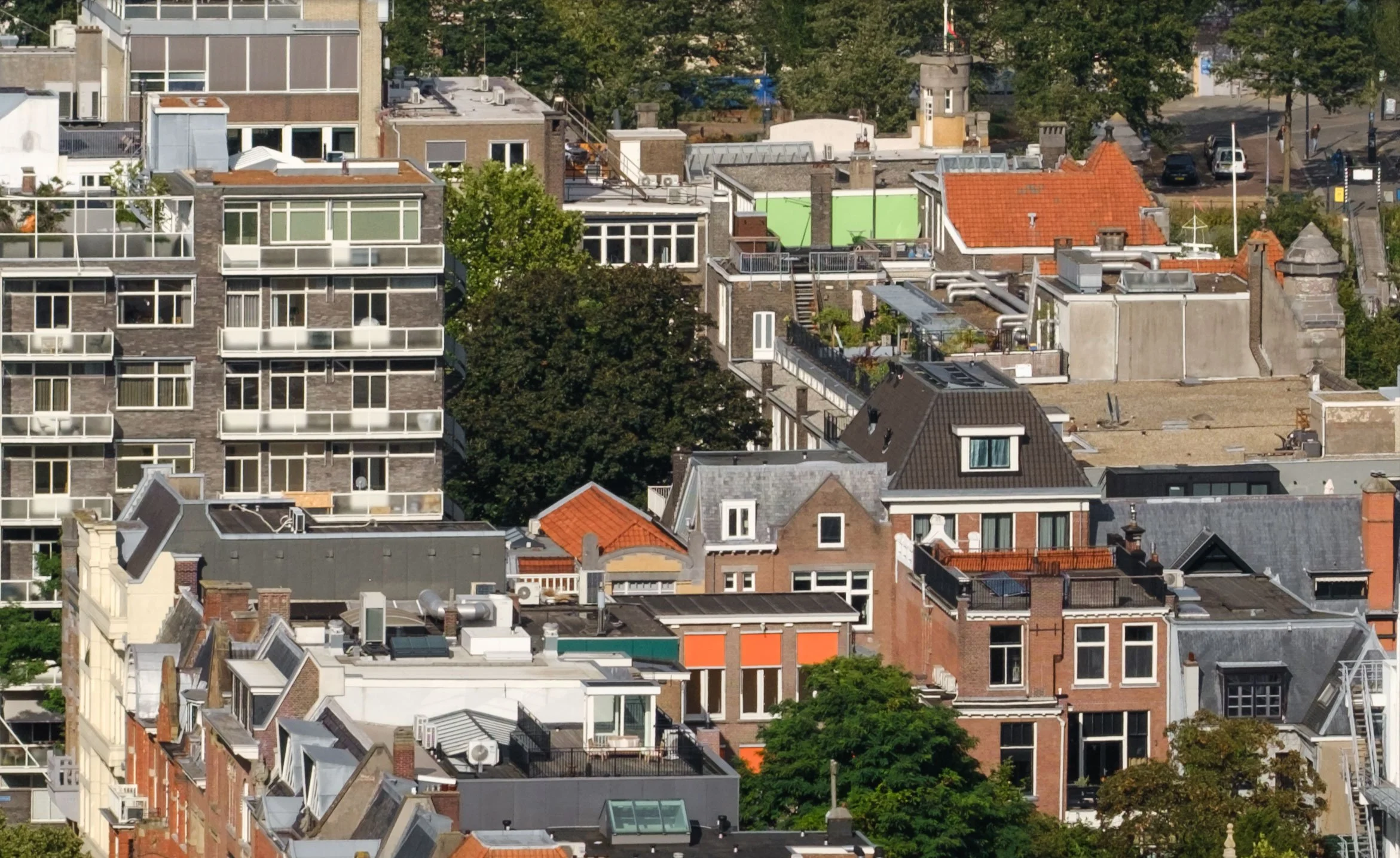 100% crop dense rooftops, apartment buildings and tree-lined streets in Rotterdam viewed from the Euromast.