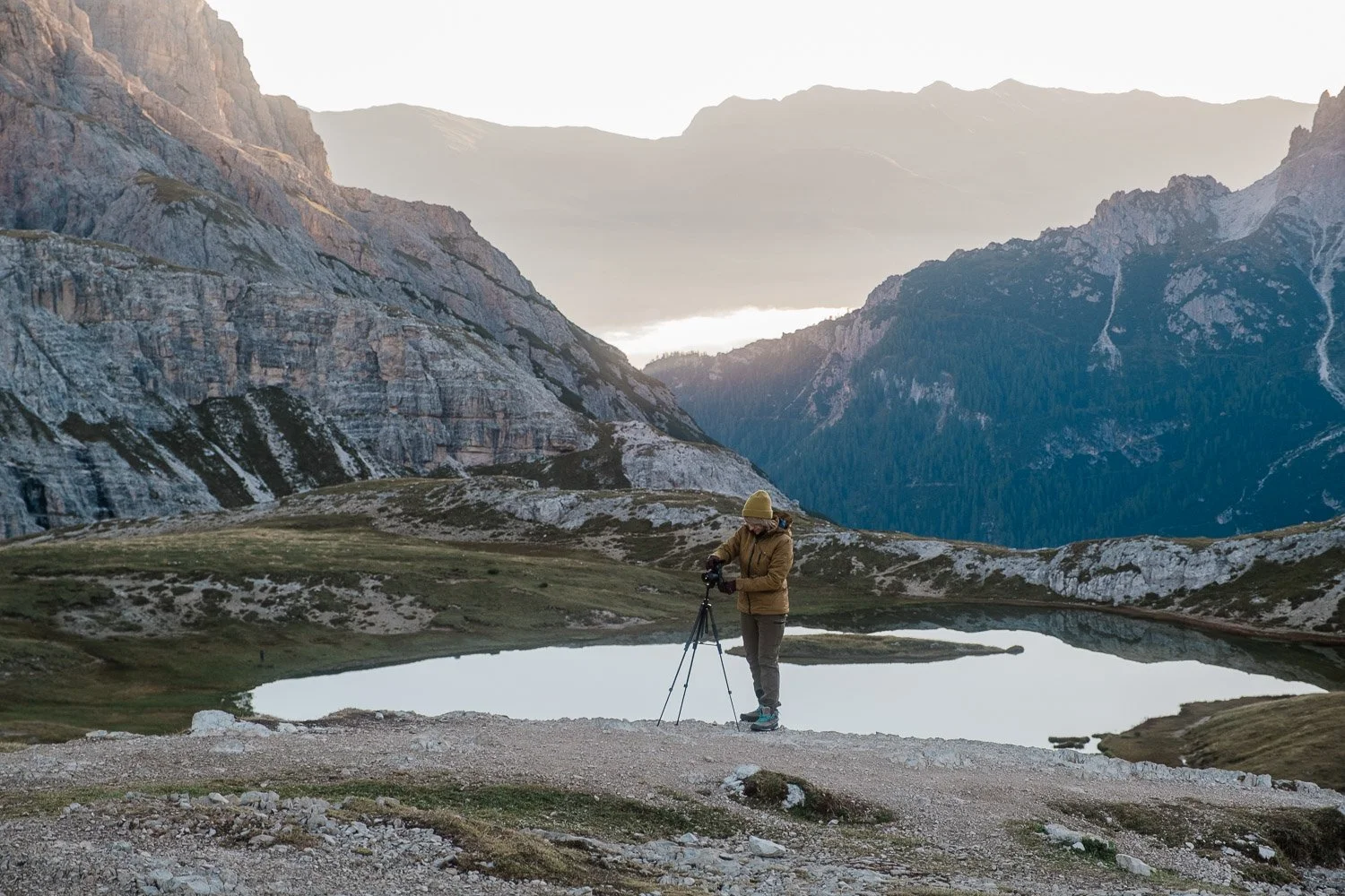 A photographer beside an alpine lake before sunrise near Tre Cime di Lavaredo.