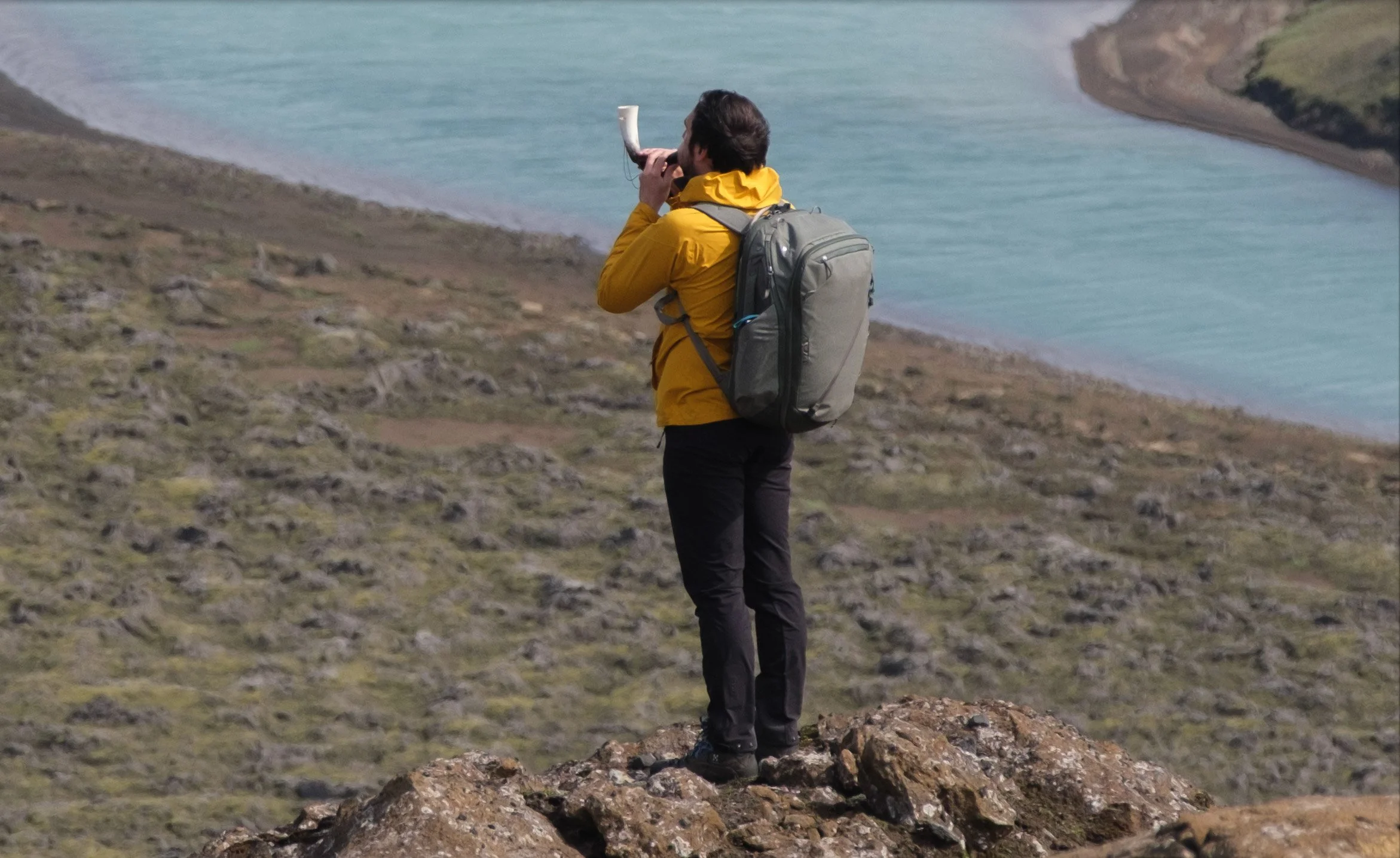 100% crop of a photographer in a yellow jacket and backpack from an Iceland photograph made with the Fujinon 50–140mm and 1.4× teleconverter.