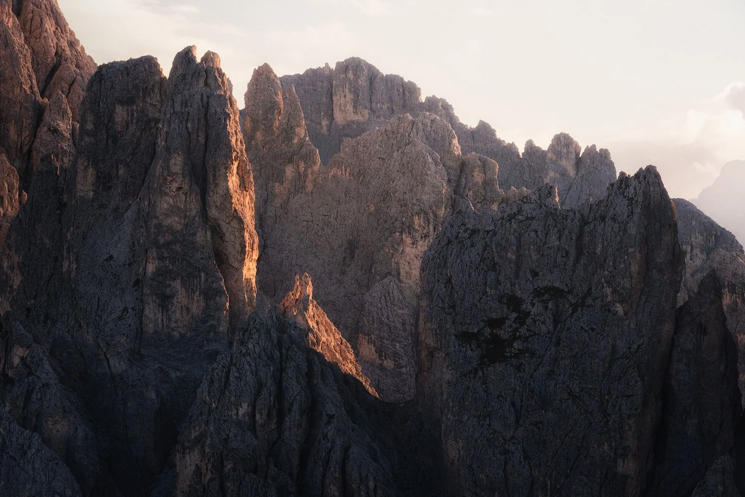 Evening light catching the jagged peaks of Cadini di Misurina above deep mountain shadows.