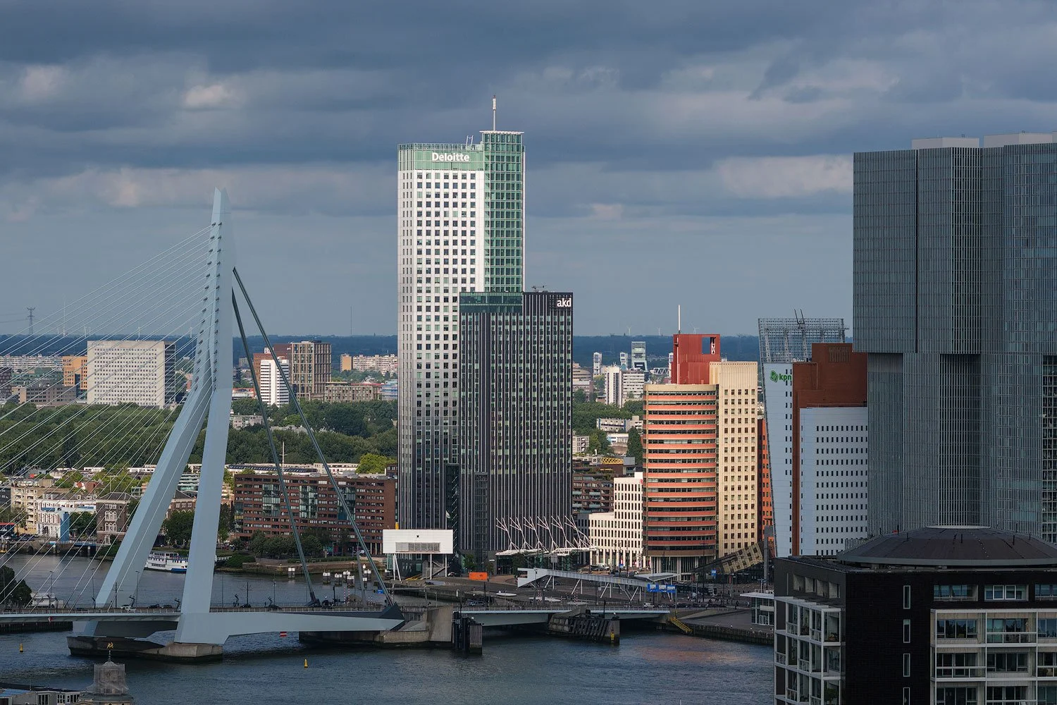 Telephoto view of the Erasmus Bridge and central Rotterdam skyline beneath dark clouds, seen from the Euromast.