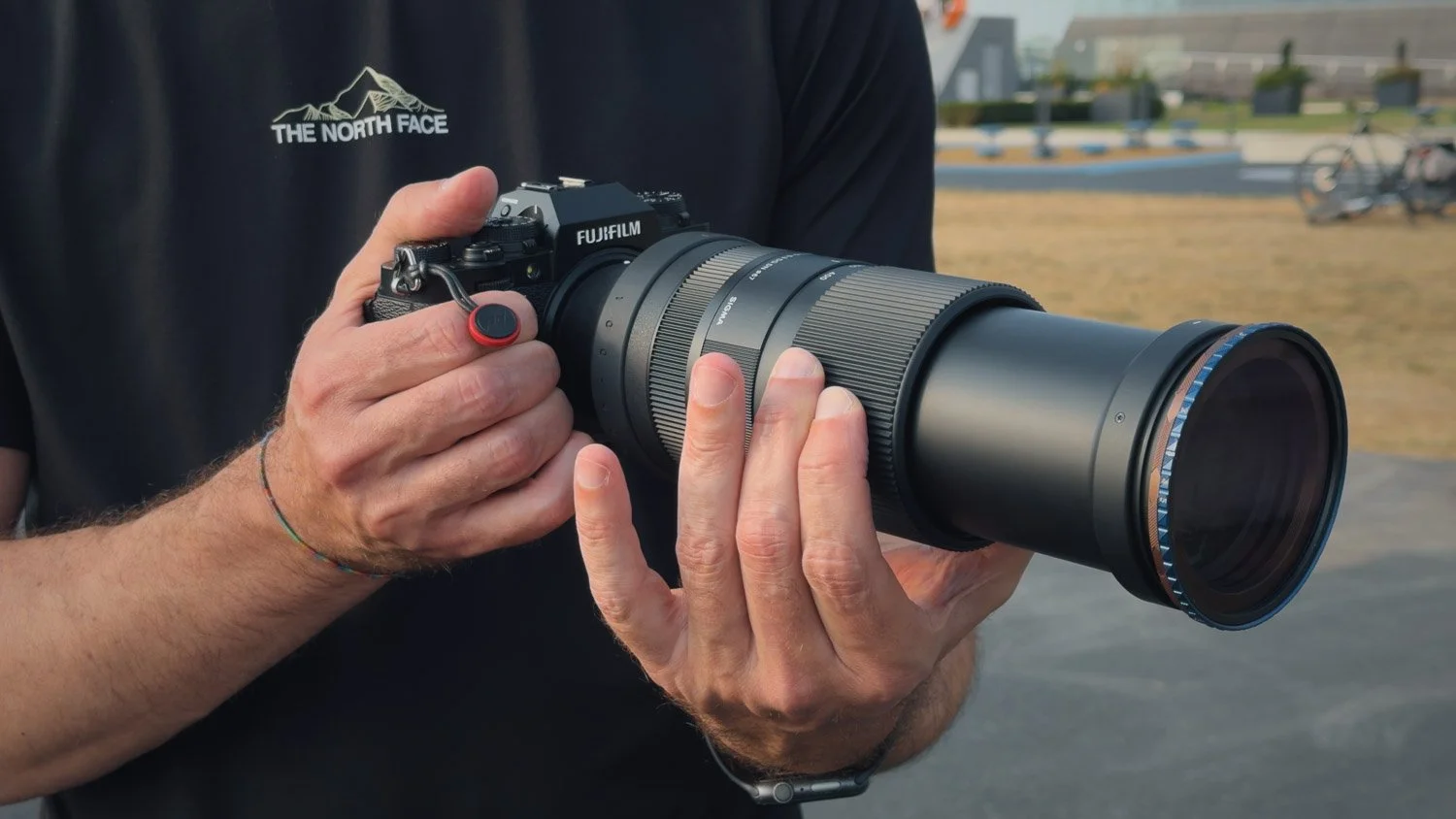 Photographer holding a Fujifilm X-T4 fitted with the Sigma 100–400mm lens and lens hood.