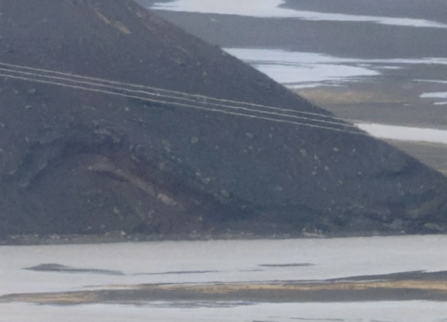 300% crop showing separated power lines and softened volcanic textures through hazy air in the Icelandic Highlands.