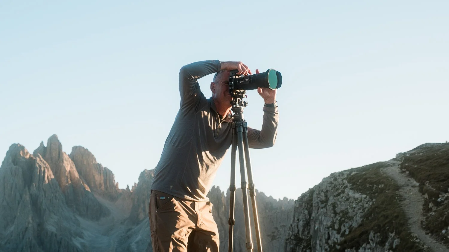 A workshop participant composing a photograph with a tripod-mounted telephoto lens at Cadini di Misurina.