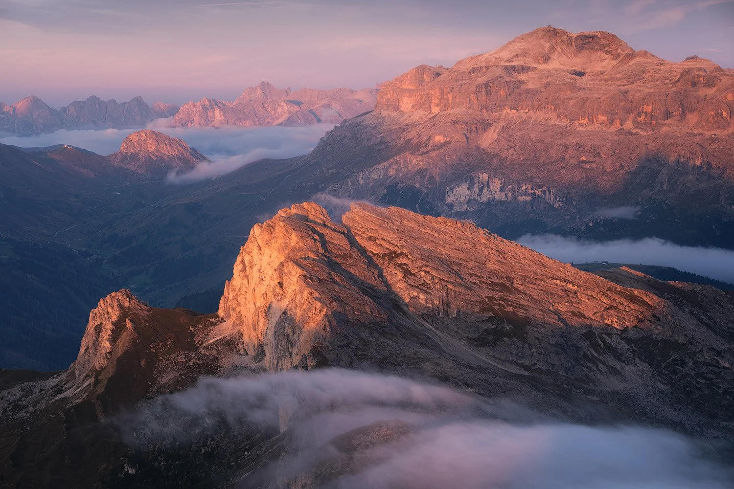 Warm sunrise light across the Dolomites, with clouds filling the valleys below Lagazuoi.