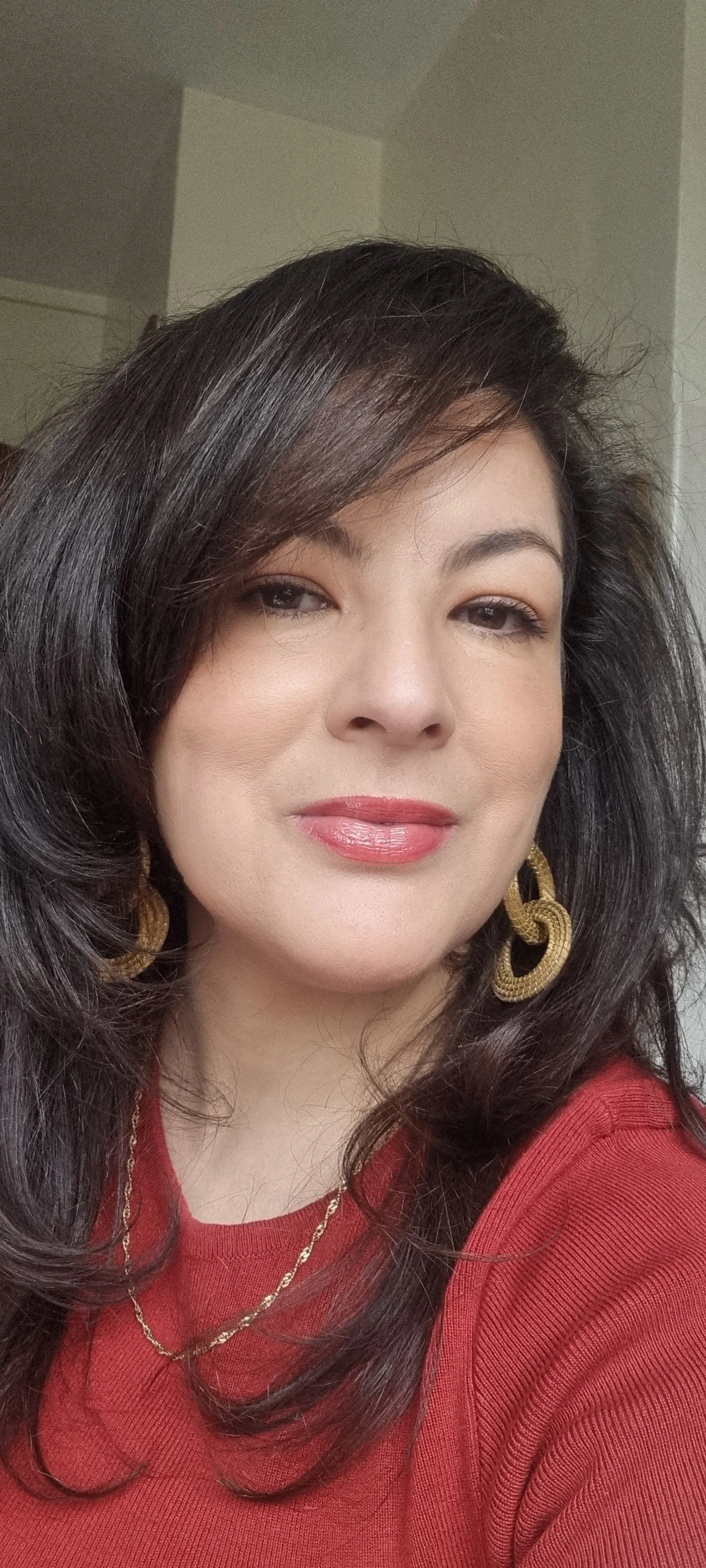 Haya smiling with a red shirt and gold necklace