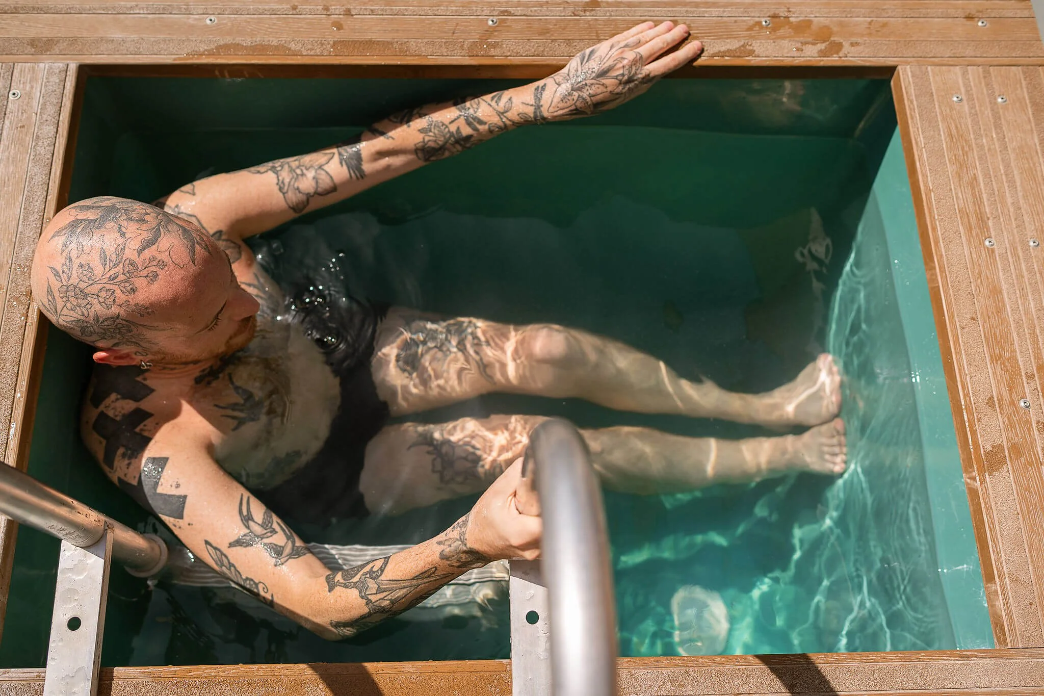 sauna bather enjoying the cold plunge in clear water at Walthamstow Community Sauna Baths London