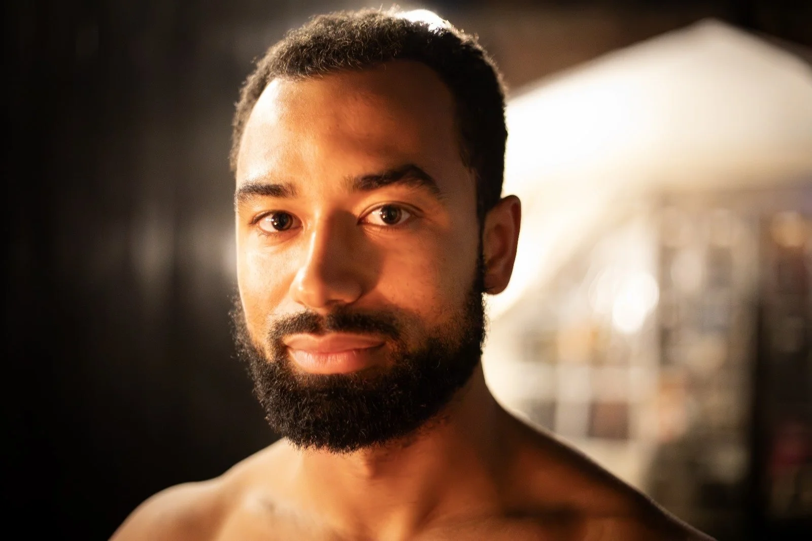 Portrait of a bearded man, softly lit in a dark wooden sauna