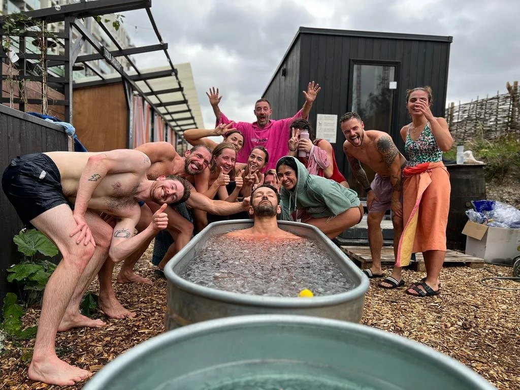 Group of sauna goers posing for the camera while someone cold plunges at Stratford community sauna