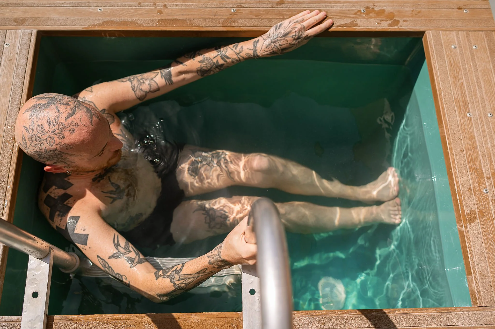 sauna bather enjoying the cold plunge in clear water at Walthamstow Community Sauna Baths London