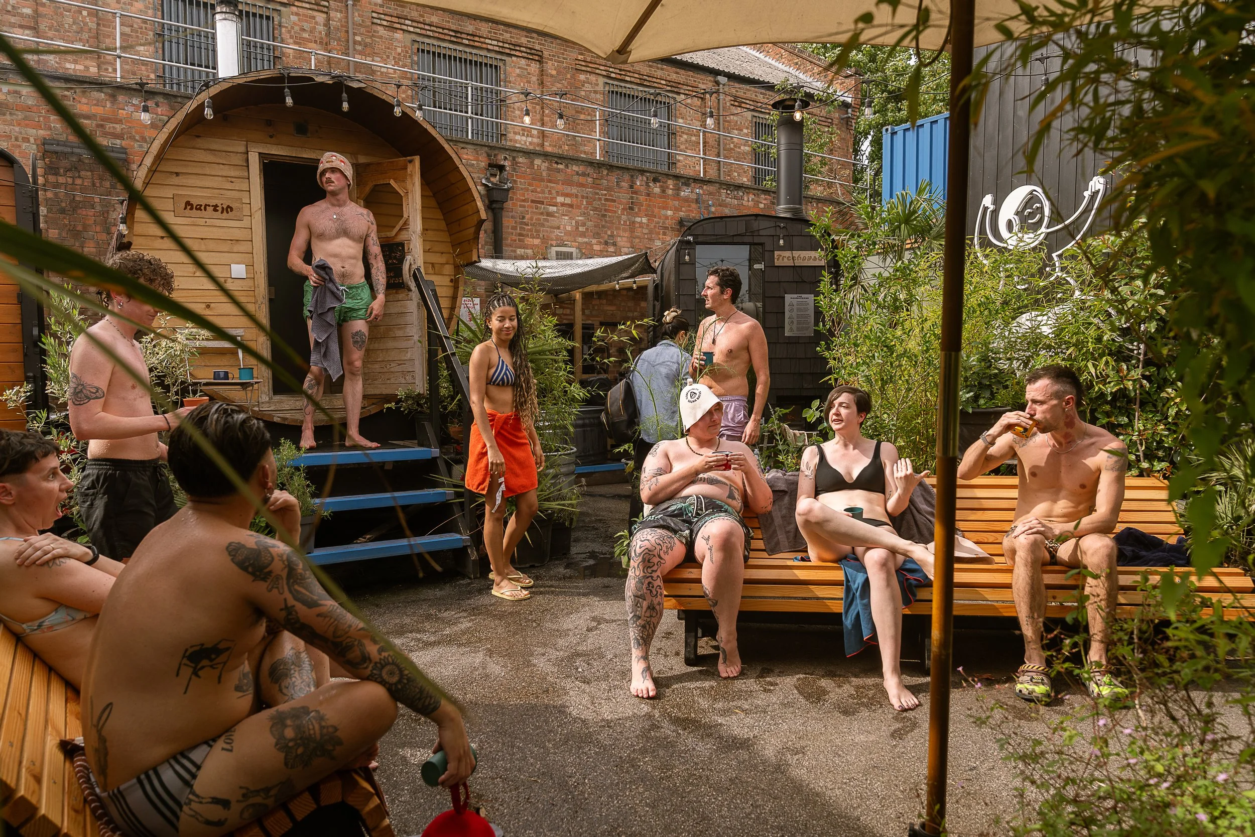 sauna bathers relaxing in the decompression zone chatting on benches at hackney wick community sauna baths london
