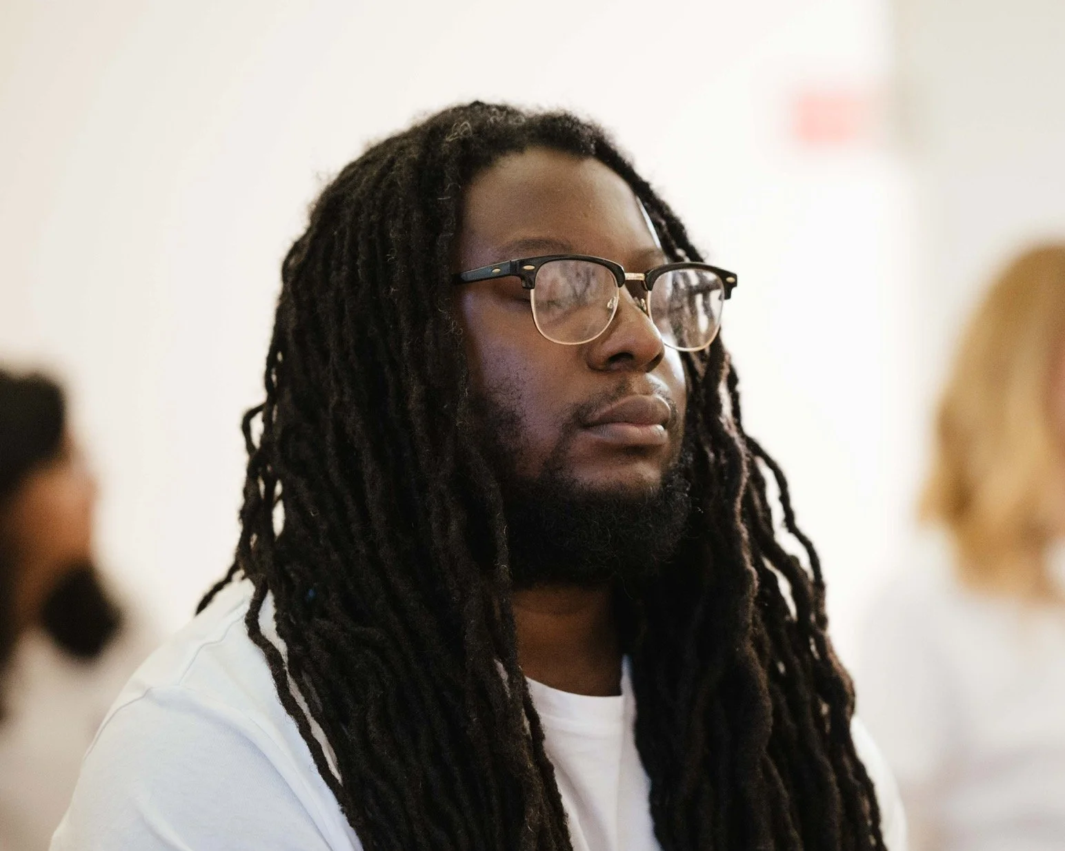 practitioner tony sitting with eyes closed wearing glasses and white tshirt