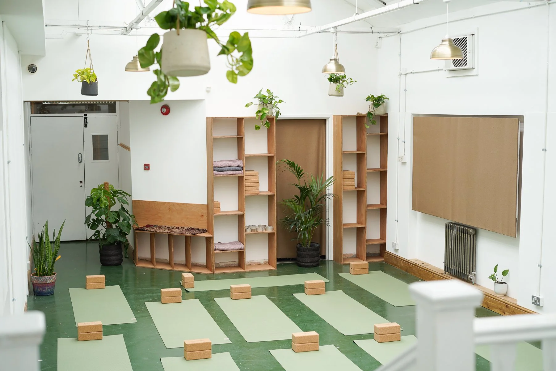A room with yoga mats, yoga bricks and plants