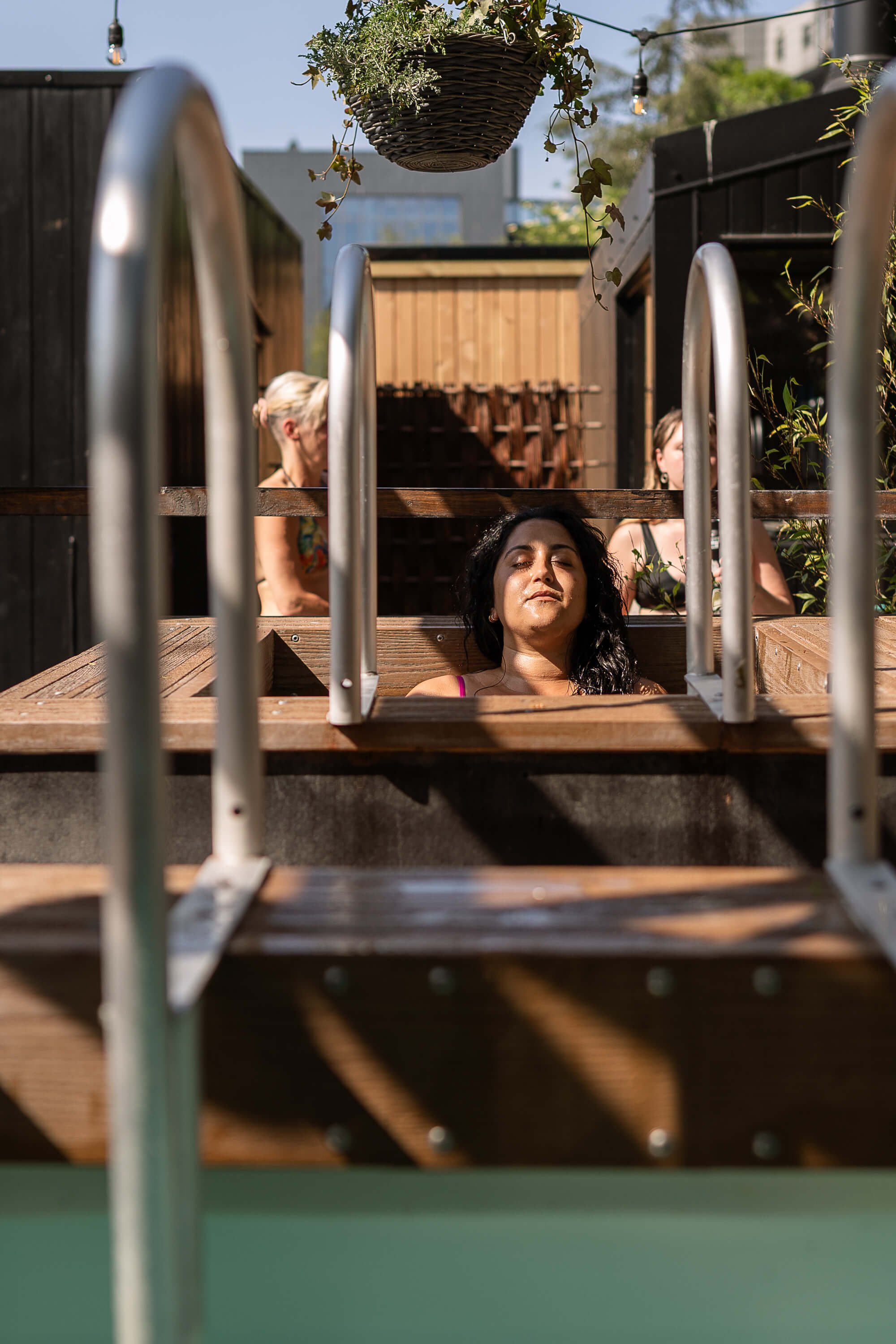 bather relaxing in one of the cold plunges eyes closed metal handles Camberwell Community Sauna Baths London