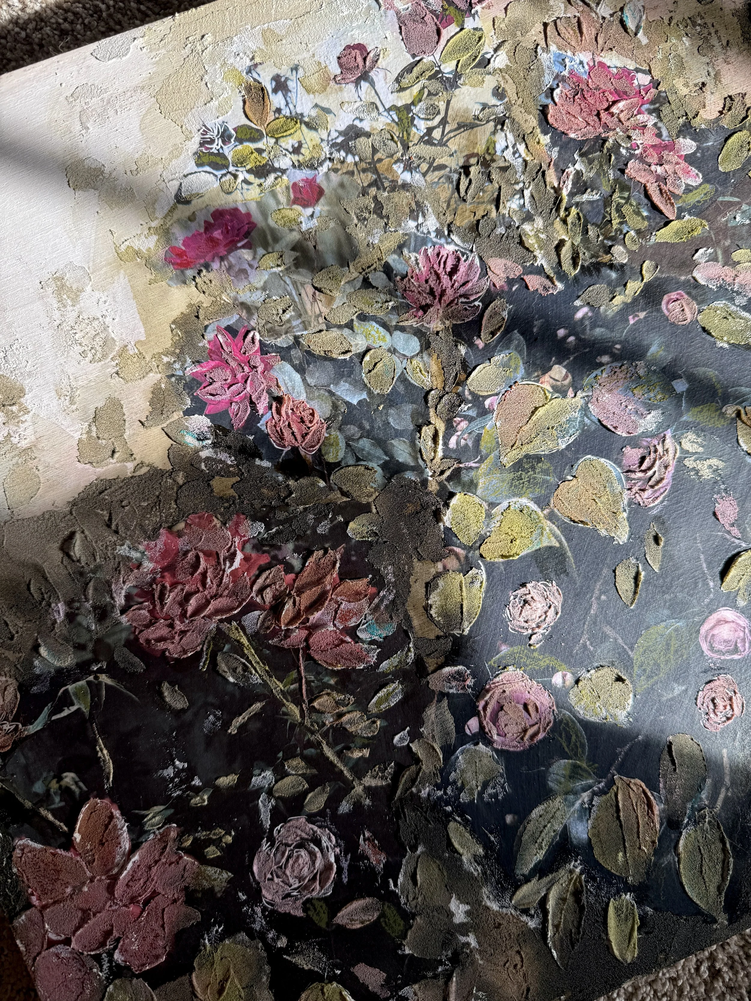 A floral painting or print featuring pink, purple, and cream-colored roses with green leaves, set against a dark background with some textured and abstract elements.