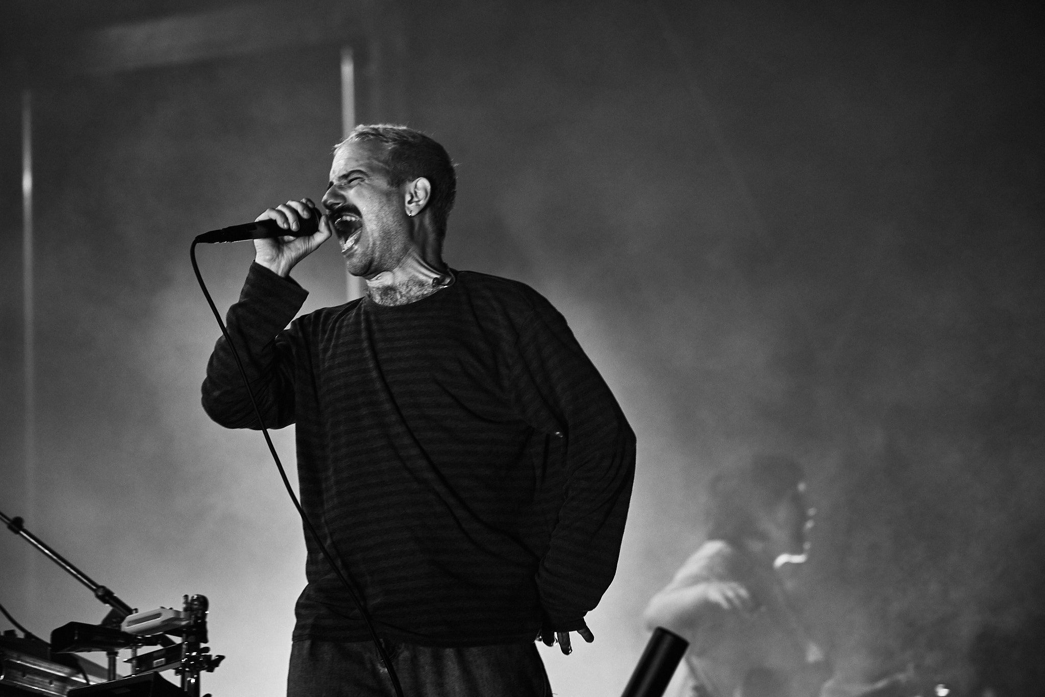 Ein singender Mann mit einem Mikrofon in der Hand, offensichtlich beim Auftritt, in Schwarz-Weiß-Fotografie.
