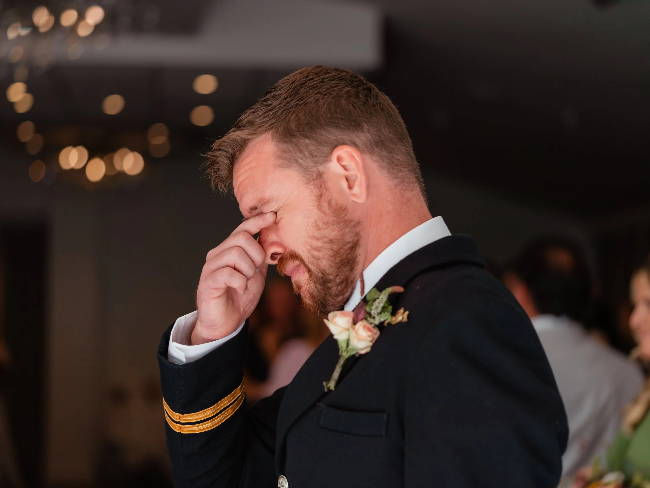 An emotional groom crying during his wedding ceremony wearing a Royal Navy uniform.