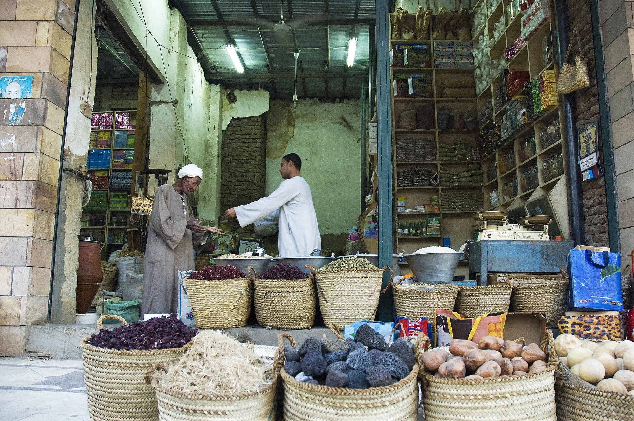At the Spice Market — 
Giza, Egypt.

The elder buyer holds out his graceful hands almost as if he is receiving alms. He makes a simple transaction feel sacred, the young vendor oblivious of his bestowal. They are the magic of Egypt that is beauty in 