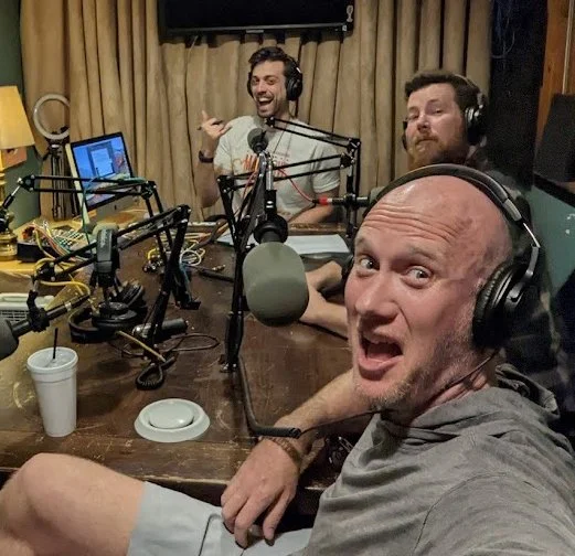 Al Doan and Bo Fishback at the podcast mics in headphones, with a third person.