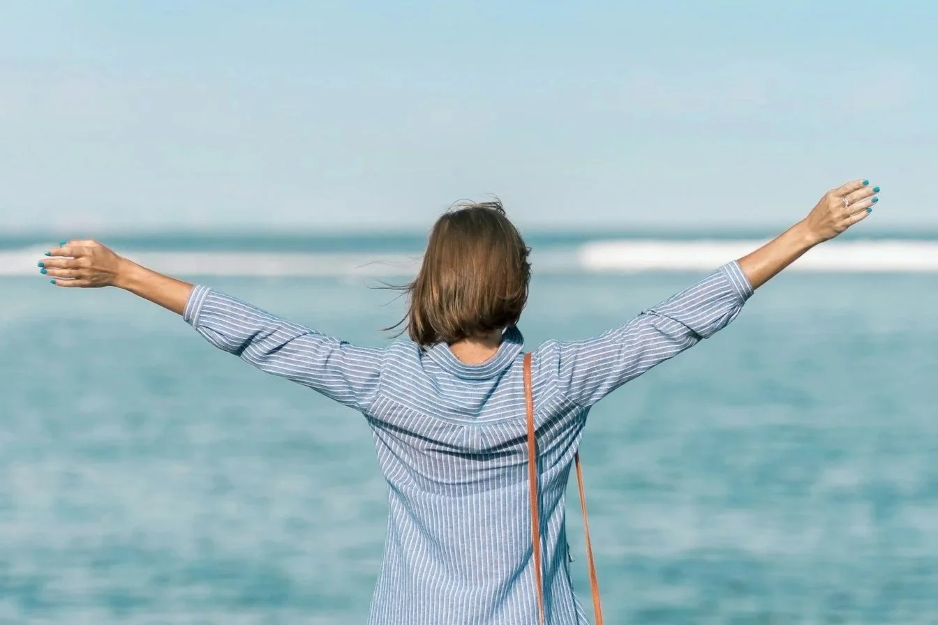 a woman outdoors with her arms spread out