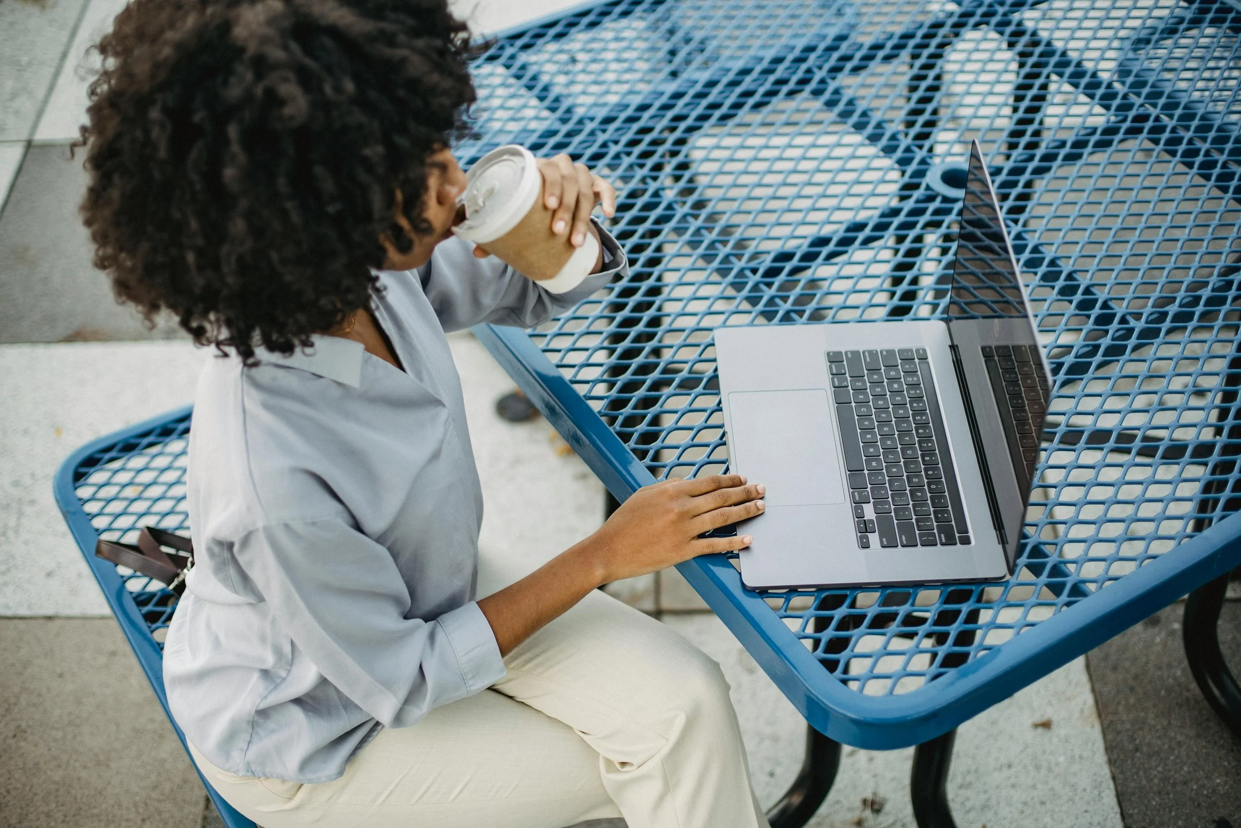 a woman drinking coffee and using a laptop