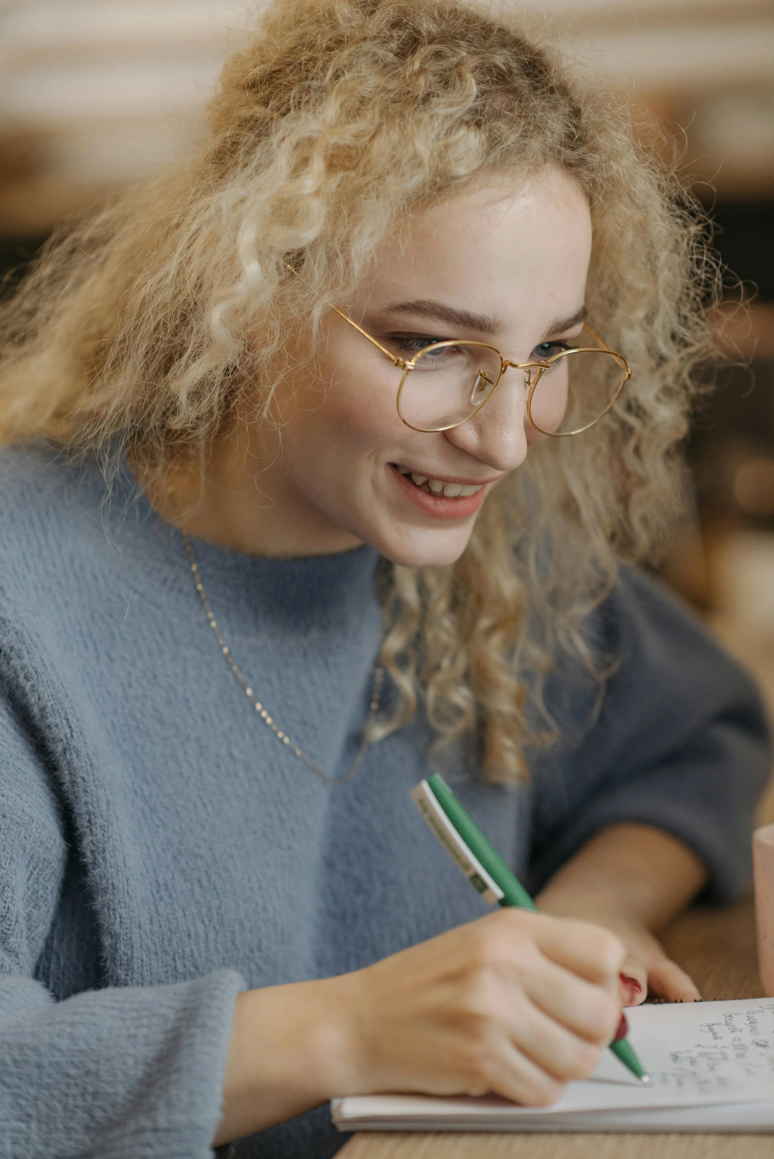 blonde woman in blue sweater writing