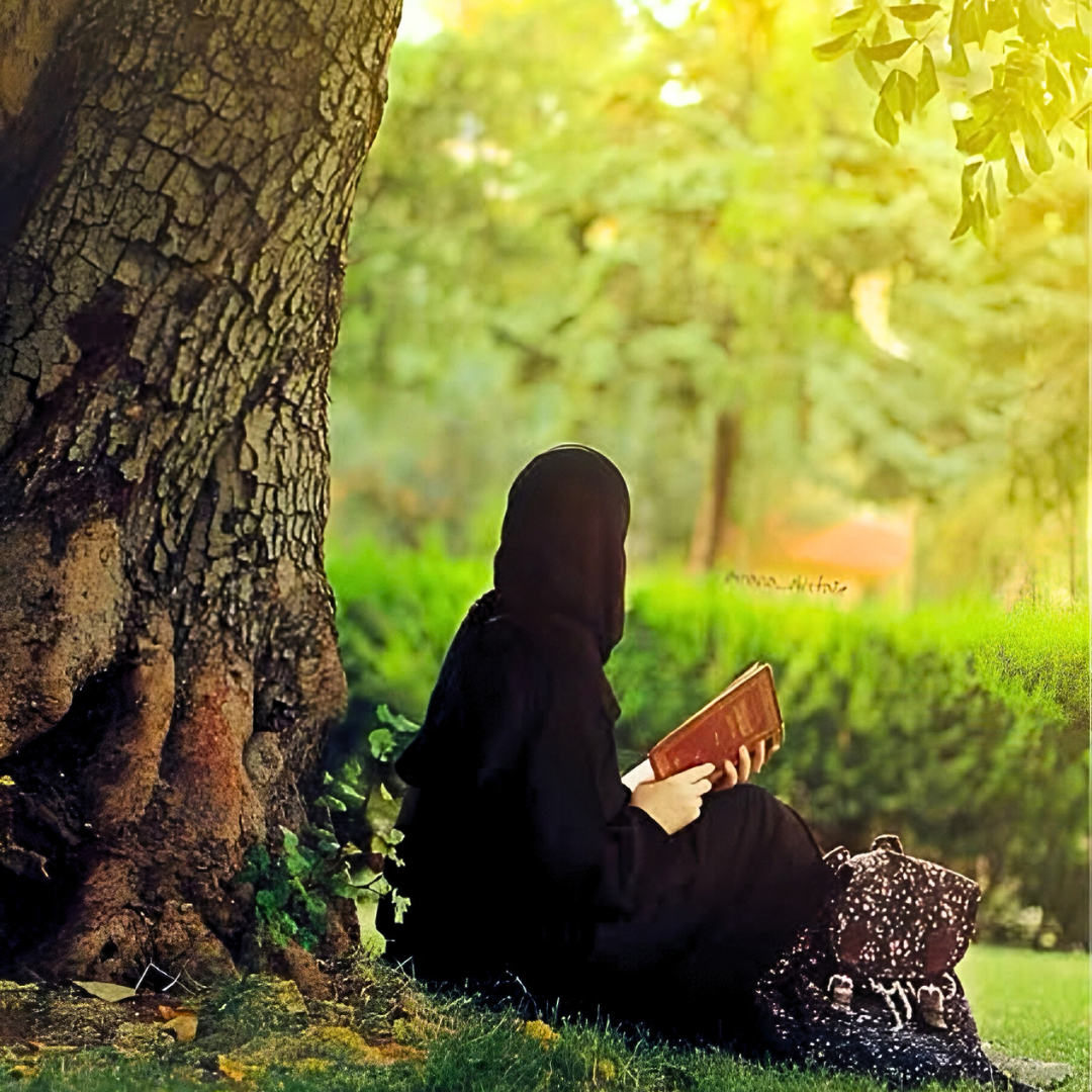 Image of a Muslim woman sitting under the shade of a tree.